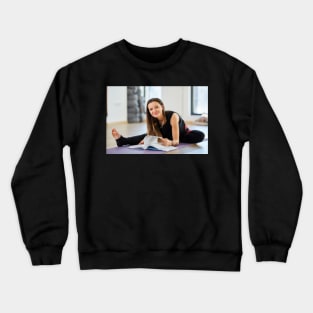 Young woman reading a yoga book Crewneck Sweatshirt